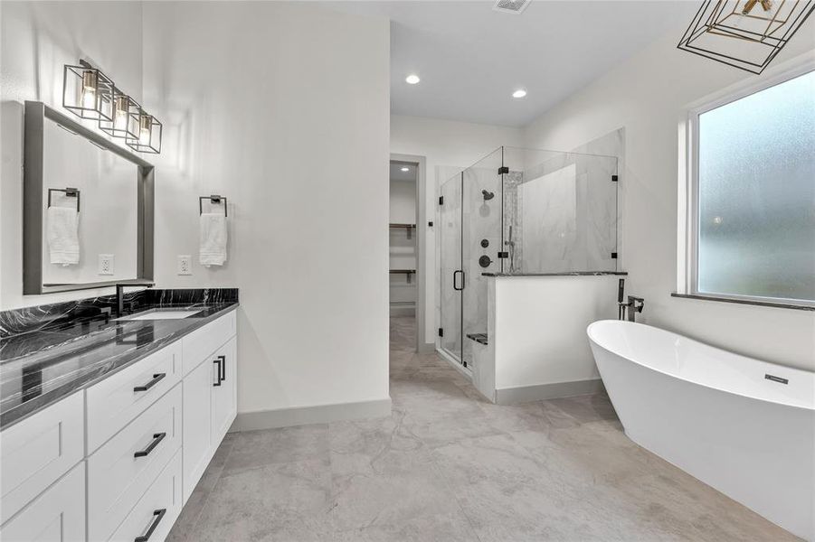 Master suite bathroom with a freestanding tub, glass-enclosed shower, frosted window, and geometric light fixture.