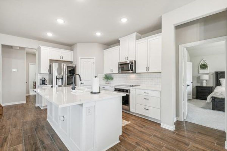 Kitchen featuring white cabinets, dark carpet, appliances with stainless steel finishes, backsplash, and a kitchen island with sink