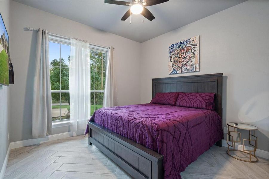 Bedroom featuring ceiling fan, light parquet flooring, and multiple windows