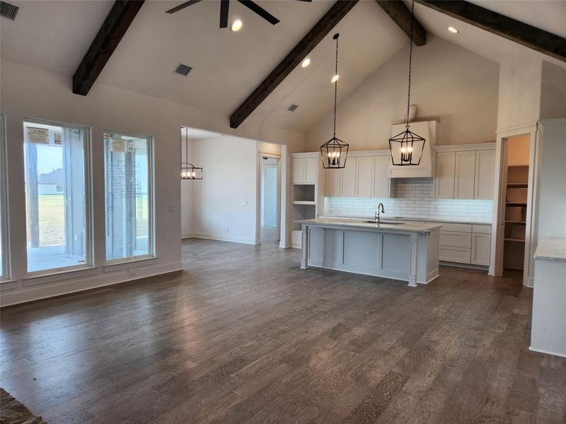 Kitchen featuring beamed ceiling, a center island with sink, and dark hardwood / wood-style flooring