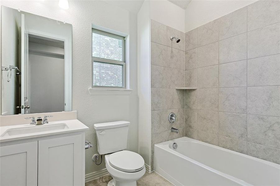 Full bathroom featuring tiled shower / bath, vanity, and toilet