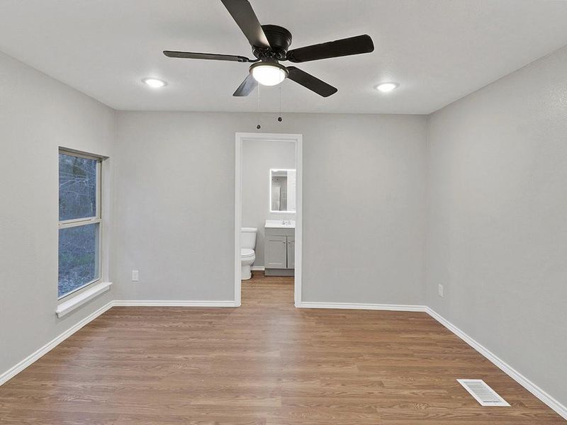 Unfurnished bedroom with connected bathroom, light hardwood / wood-style floors, and ceiling fan