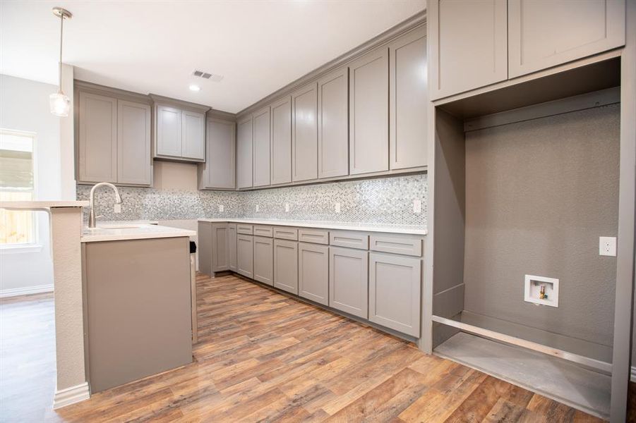 Kitchen featuring sink, tasteful backsplash, wood-type flooring, and gray cabinets