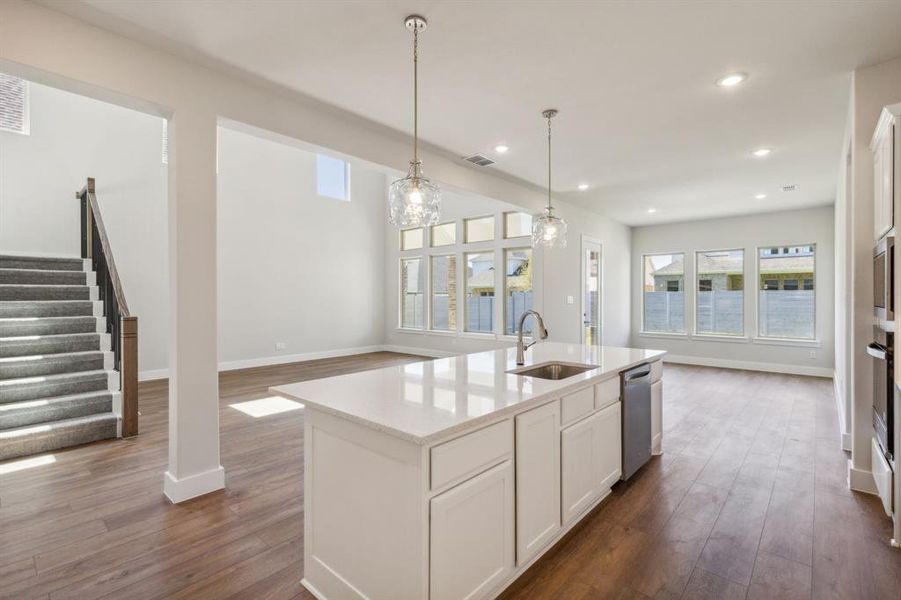 Kitchen featuring an island with sink, white cabinetry, dark hardwood / wood-style floors, dishwasher, and sink