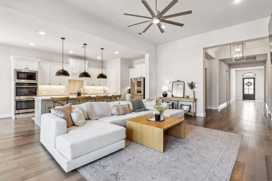 Living room with ceiling fan and light hardwood / wood-style flooring