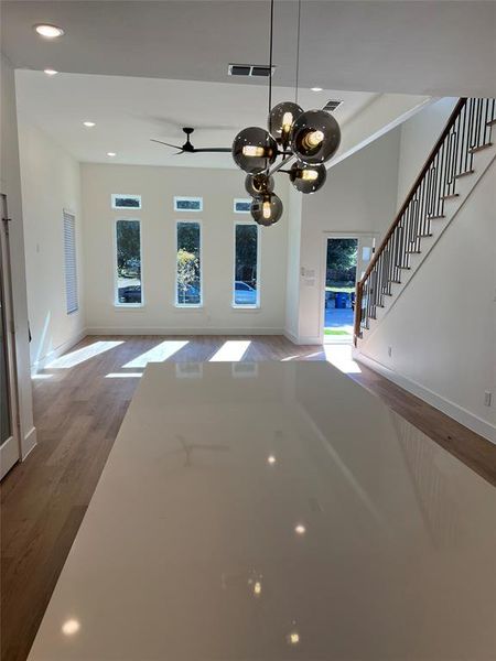 Unfurnished living room featuring ceiling fan with notable chandelier and hardwood / wood-style flooring