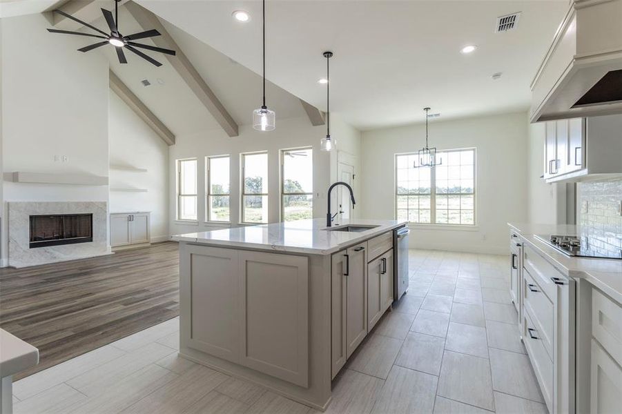 Kitchen with an island with sink, ceiling fan with notable chandelier, hanging light fixtures, and sink