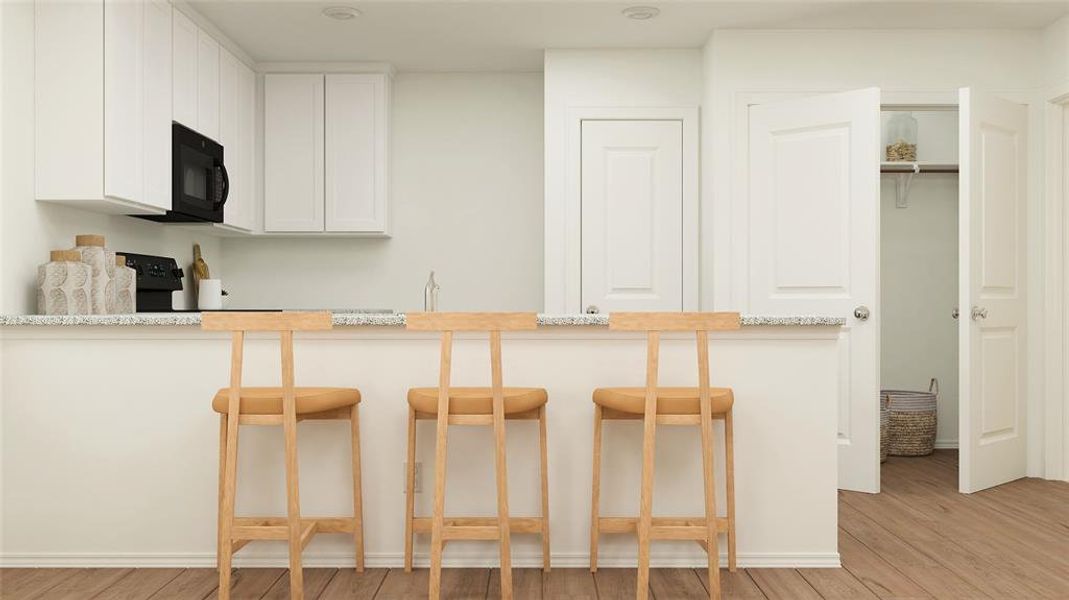 Kitchen featuring white cabinets, light hardwood / wood-style floors, light stone countertops, and kitchen peninsula