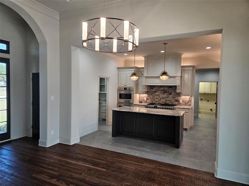 Kitchen featuring pendant lighting, dark wood-type flooring, white cabinets, a kitchen island, and decorative backsplash