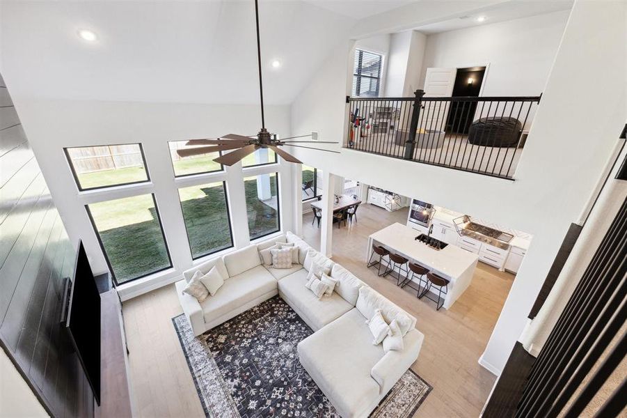 The upper-level balcony overlooks the living area, enhancing the sense of openness.The view includes a cozy living room, a spacious dining area, and a glimpse of a stylish kitchen, all unified by sleek hardwood floors.