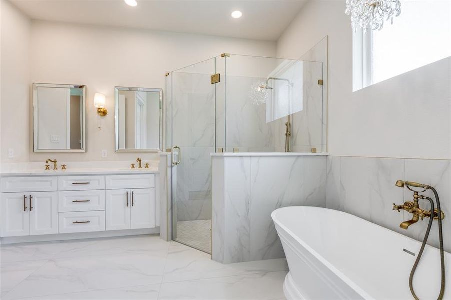 Bathroom with tile patterned flooring, independent shower and bath, double sink vanity, and an inviting chandelier