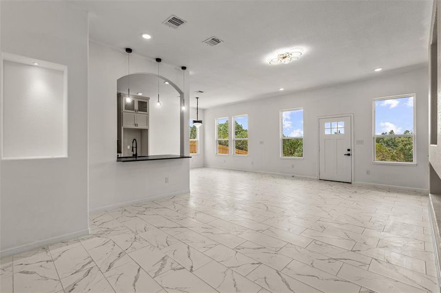 Unfurnished living room with a wealth of natural light, sink, and light tile flooring