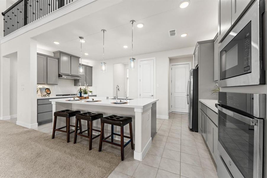 This home features a luxurious kitchen designed for culinary enthusiasts. It boasts a huge countertop with stylish pendant and recessed ceiling lights, complementing the sleek stainless steel appliances.