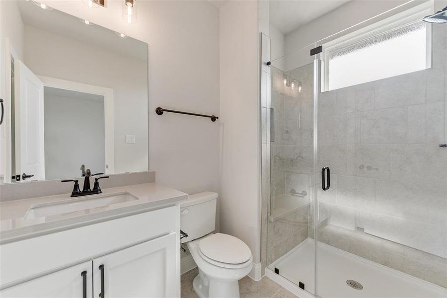 Bathroom featuring tile patterned flooring, an enclosed shower, vanity, and toilet