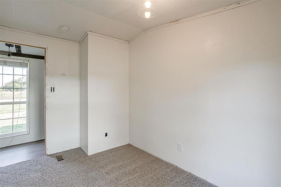 Spare room with a wealth of natural light, carpet floors, and vaulted ceiling