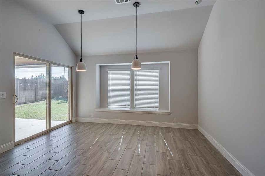 Unfurnished dining area with light hardwood / wood-style floors and high vaulted ceiling