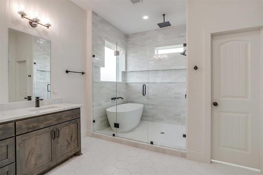 Bathroom featuring a healthy amount of sunlight, vanity, and plus walk in shower