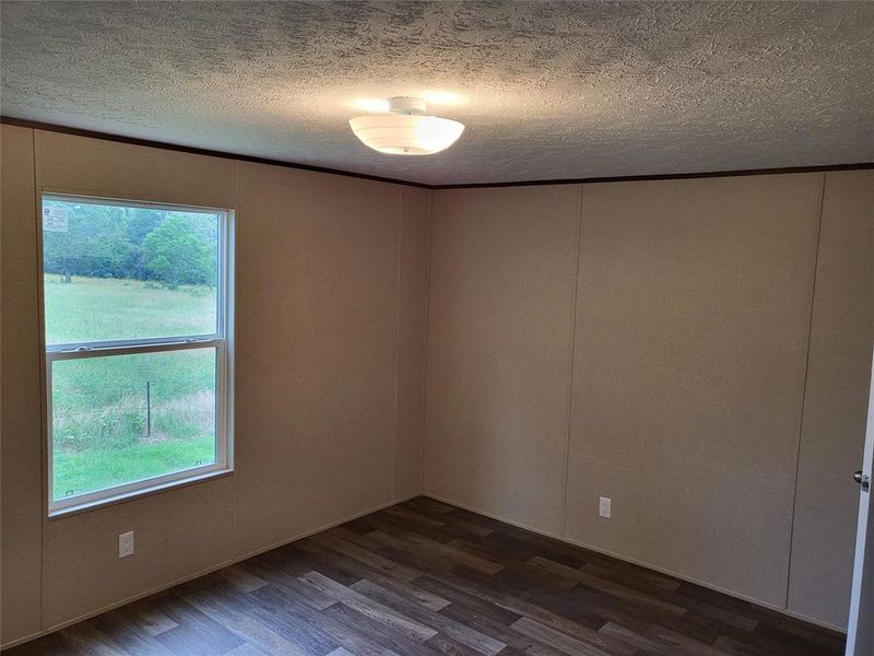 Empty room with dark hardwood / wood-style flooring and a textured ceiling