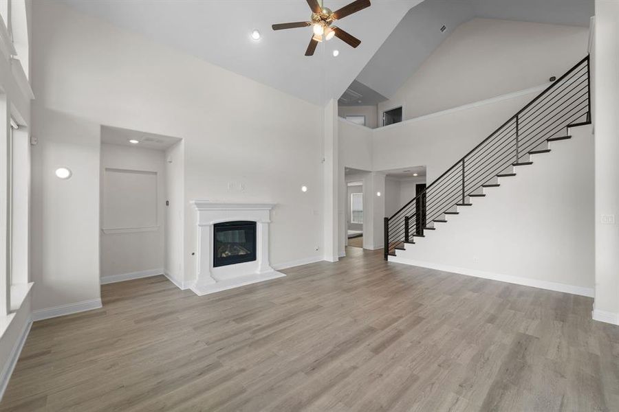 Unfurnished living room with ceiling fan, high vaulted ceiling, and light hardwood / wood-style floors