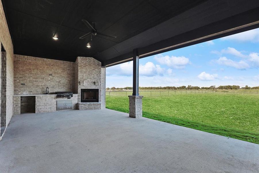 View of patio with an outdoor kitchen, ceiling fan, and a rural view