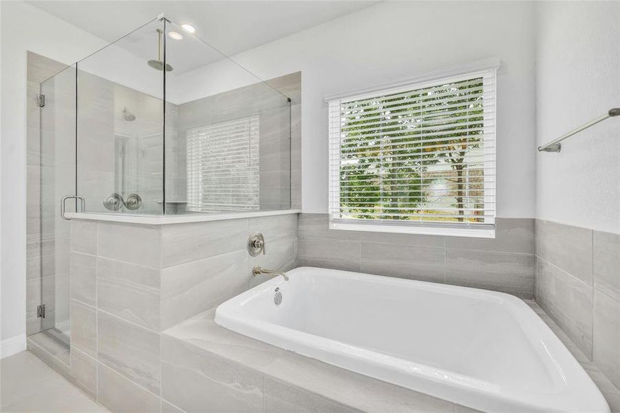 Master bathroom Tub and separate Shower with a Seat and tile flooring.