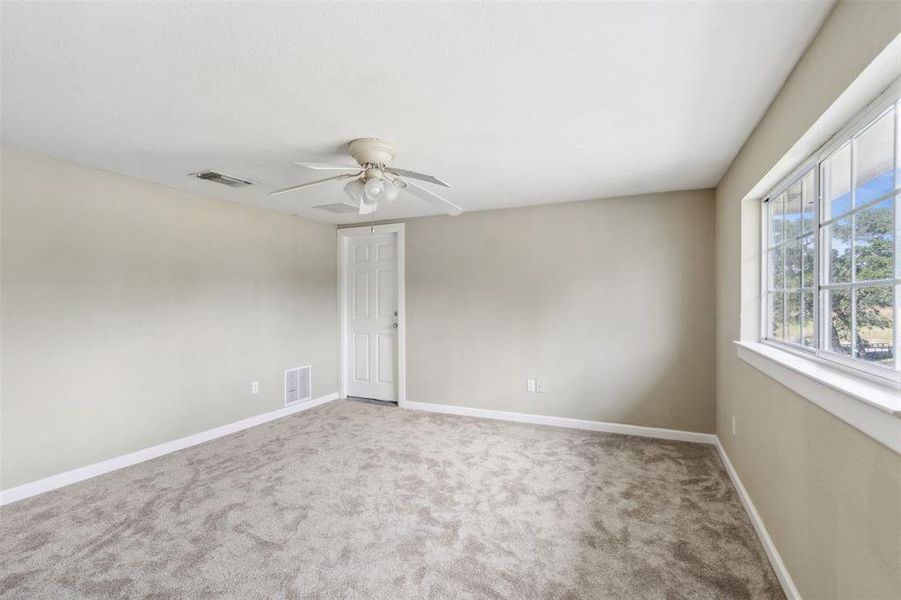 Upstairs bedroom featuring light colored carpet and ceiling fan