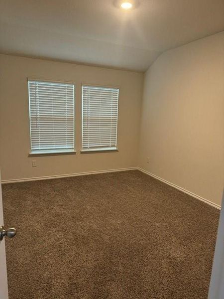 Carpeted spare room featuring lofted ceiling