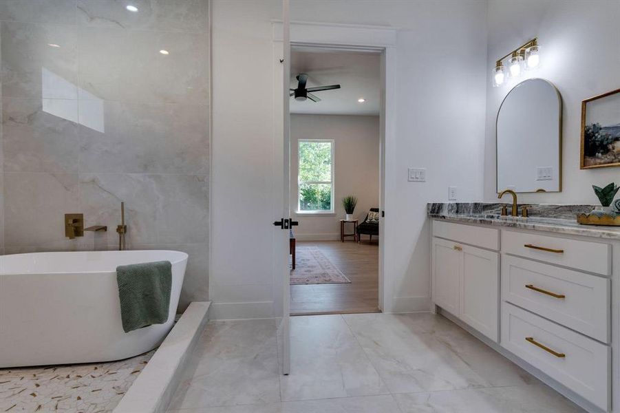 Bathroom with vanity, tile patterned floors, ceiling fan, tile walls, and a bathing tub
