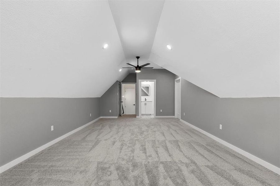 Bonus room featuring lofted ceiling, light colored carpet, and ceiling fan