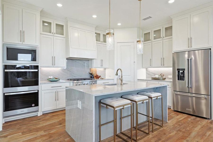 Kitchen with stainless steel appliances, sink, light hardwood / wood-style flooring, and backsplash