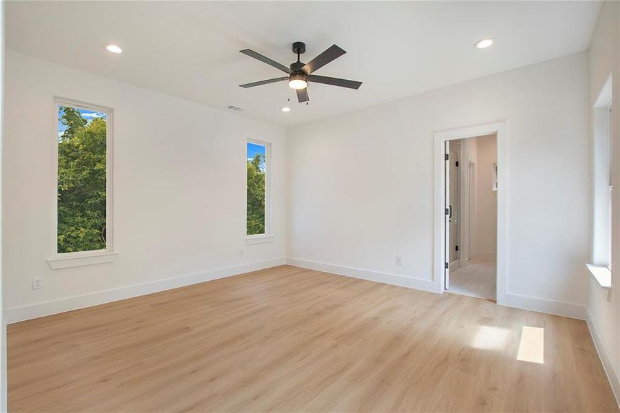 Spare room featuring ceiling fan, light hardwood / wood-style flooring, and a healthy amount of sunlight