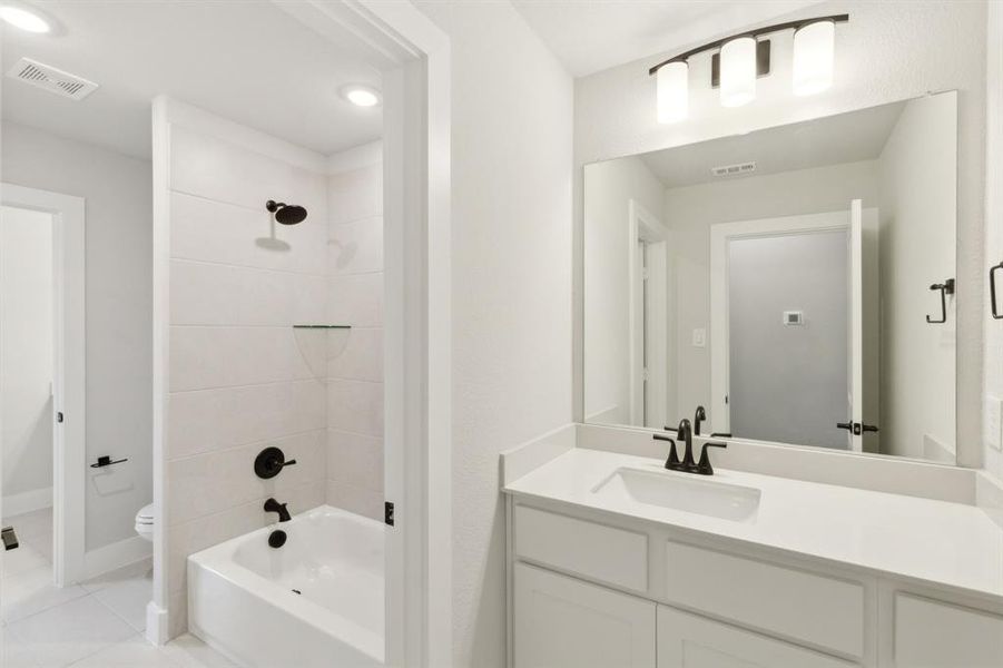 Full bathroom featuring toilet, vanity, tiled shower / bath, and tile patterned flooring