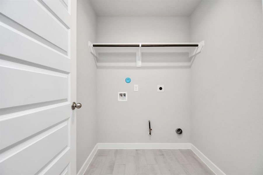 A perfect blend of functionality and comfort. Laundry room, thoughtfully equipped with shelving for effortless organization. Both gas and electric dryer connections available. Sample photo of completed home with similar plan. Actual color and selections may vary.
