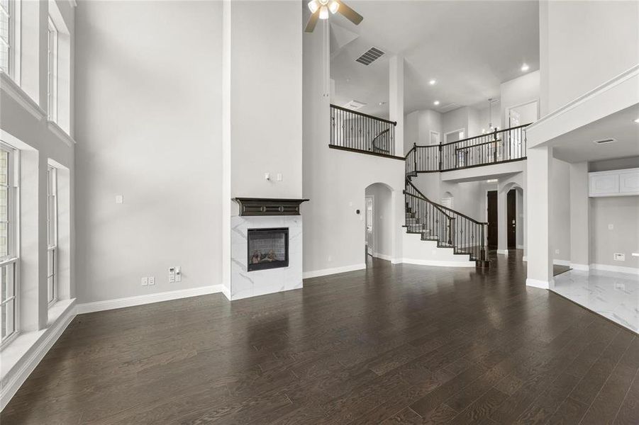 Unfurnished living room featuring dark hardwood / wood-style floors, a towering ceiling, and ceiling fan