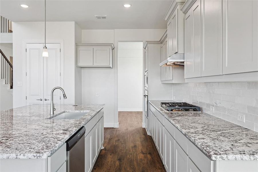 Kitchen featuring decorative light fixtures, sink, dark wood-type flooring, appliances with stainless steel finishes, and extractor fan