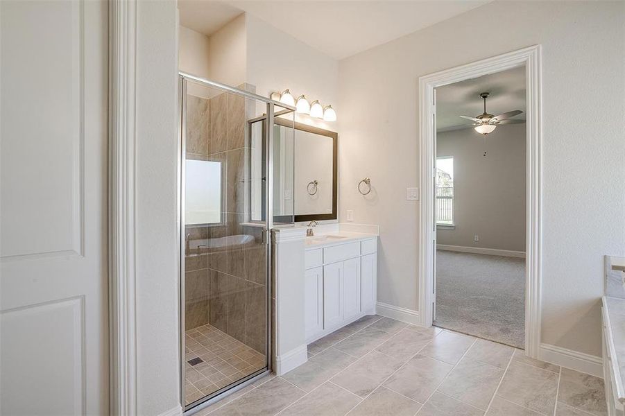 Bathroom with ceiling fan, tile patterned flooring, vanity, and walk in shower