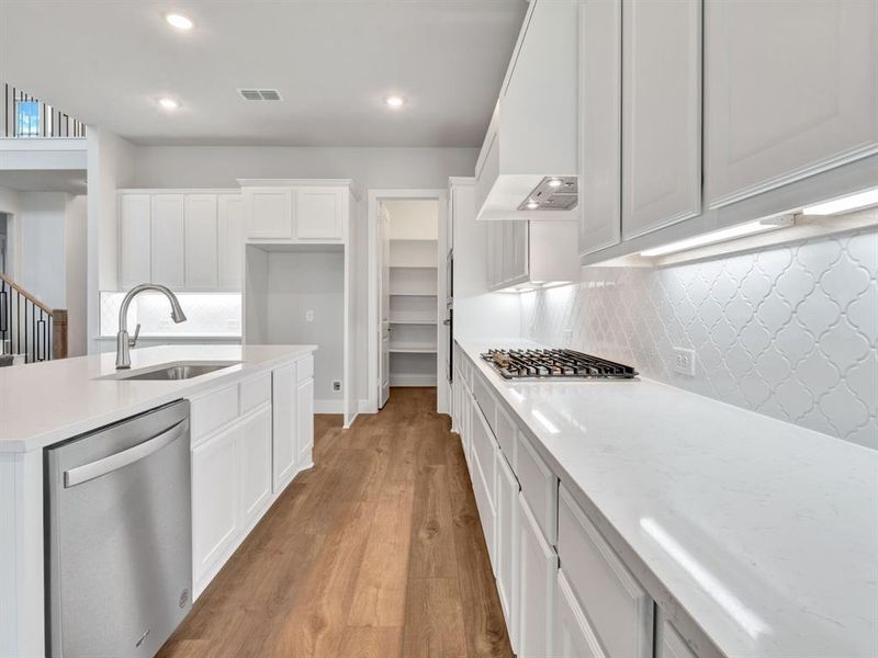 Kitchen featuring tasteful backsplash, light wood-type flooring, appliances with stainless steel finishes, and sink