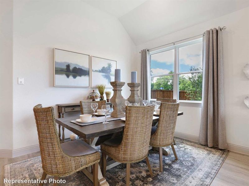 Dining room with light hardwood / wood-style flooring and vaulted ceiling