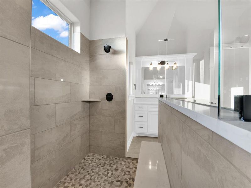 Bathroom featuring a tile shower, an inviting chandelier, and vanity