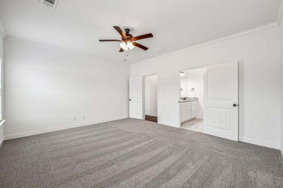 Unfurnished bedroom featuring ensuite bath, ceiling fan, ornamental molding, and light colored carpet