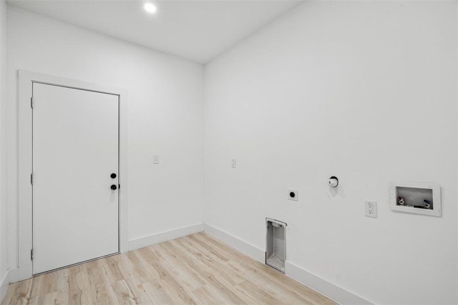 Clothes washing area featuring hookup for a washing machine, gas dryer hookup, electric dryer hookup, and light hardwood / wood-style flooring