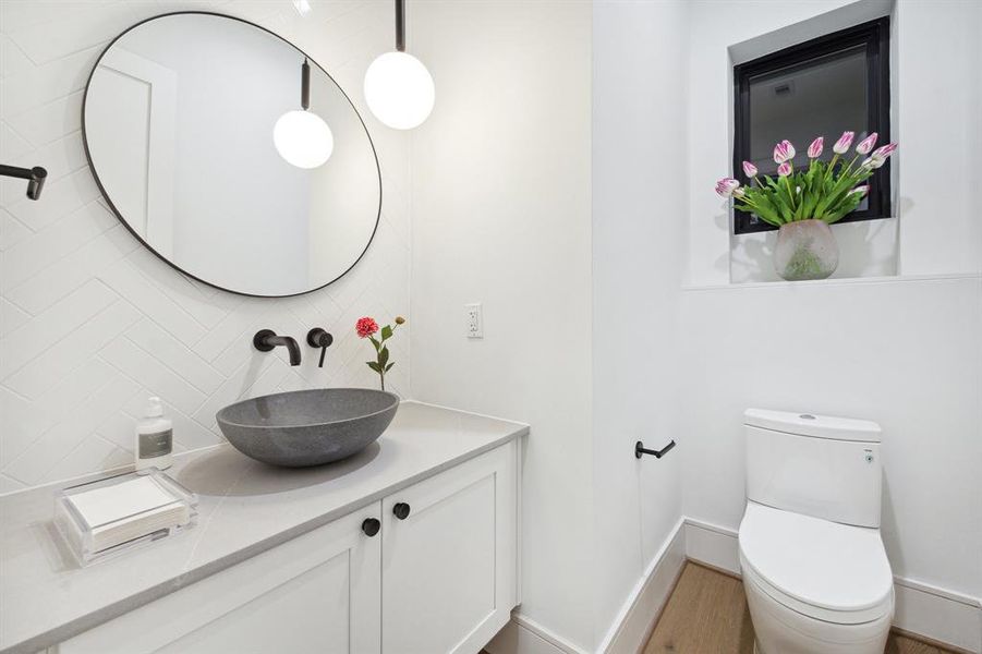 Powder Room with a Floating Cabinet, Slab Quartz Counter, Concrete Vessel Sink, Wall-Mounted Faucet. The backsplash wall is adorned with a 2" x 10" White Tile. There is also a Framed Mirror and a Single Pendant Light.