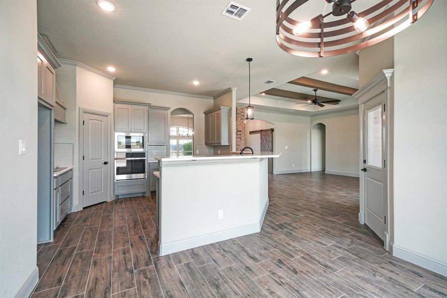 Kitchen featuring stainless steel appliances, backsplash, dark wood-type flooring, ceiling fan, and a raised ceiling