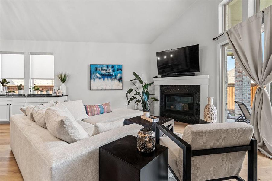 Living room featuring a high end fireplace, high vaulted ceiling, and light wood-type flooring