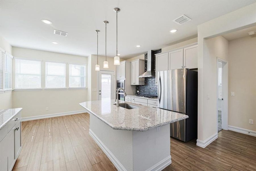 Kitchen featuring sink, an island with sink, pendant lighting, white cabinets, and appliances with stainless steel finishes