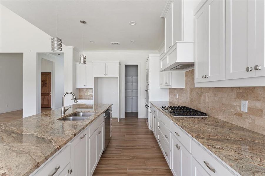 Kitchen with tasteful backsplash, light wood-type flooring, stainless steel appliances, pendant lighting, and sink