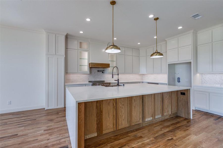 Kitchen featuring light hardwood / wood-style flooring, white cabinets, a large island with sink, and sink