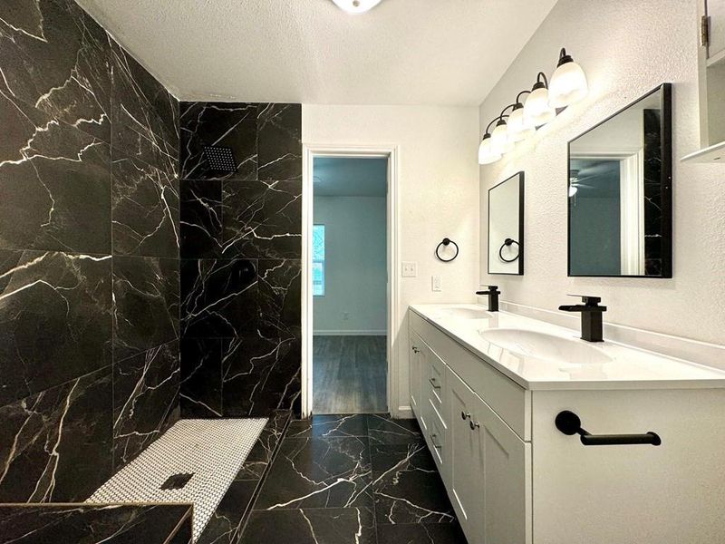 Bathroom featuring tiled shower, hardwood / wood-style flooring, and dual bowl vanity