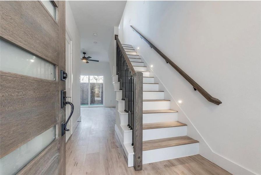 Stairway featuring a towering ceiling, hardwood / wood-style floors, and ceiling fan