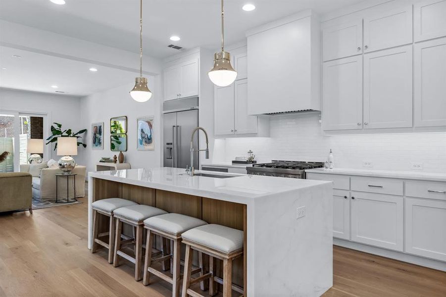 Kitchen with appliances with stainless steel finishes, sink, light wood-type flooring, an island with sink, and white cabinets